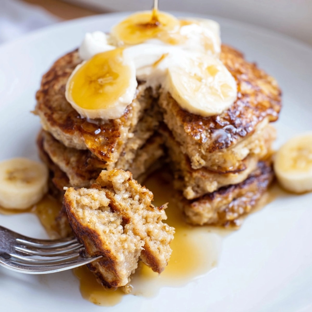 Warm, fluffy Banana Oatmeal Pancakes, with visible oat texture, cooking on a griddle.