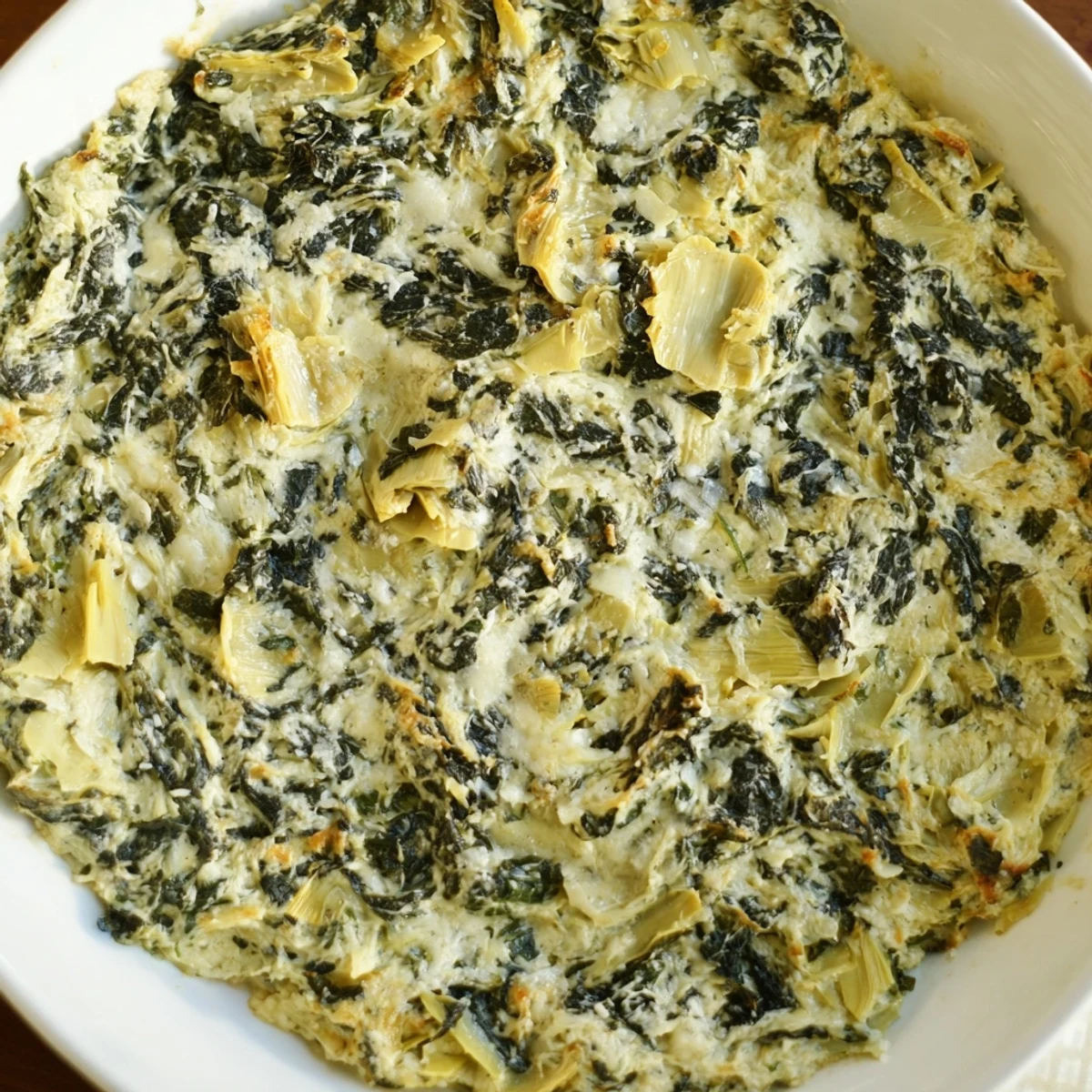A close-up of creamy, cheesy Creamy Spinach and Artichoke Dip, served hot from the oven with crackers.