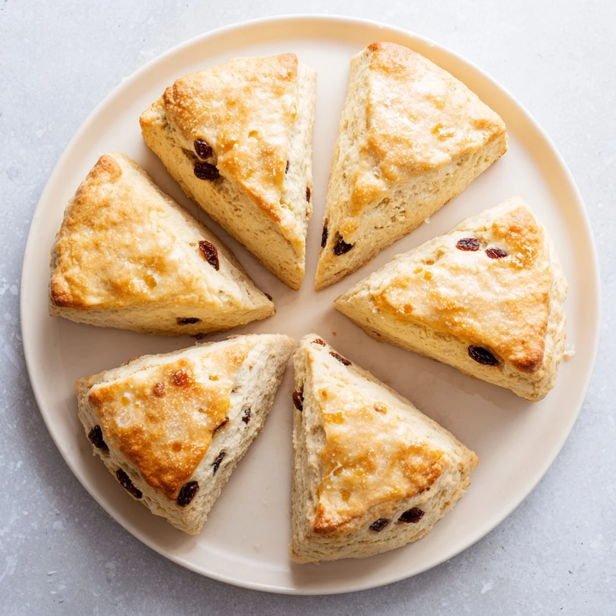 Close-up shot shows flaky scones, perfect for tea, with a dusting of flour on the side.