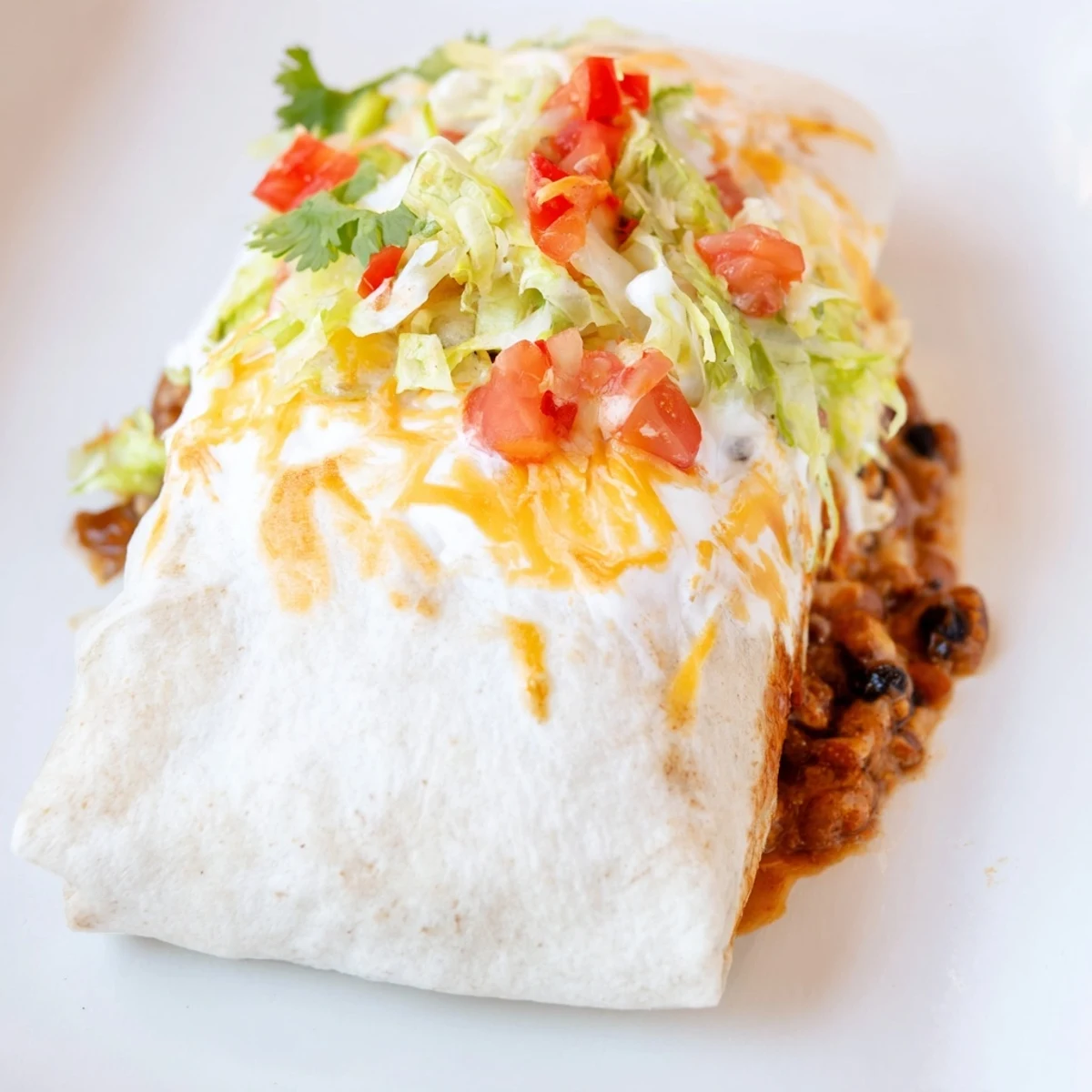 A close-up of delicious bean burritos, with melted cheese and fresh cilantro, waiting to be eaten.