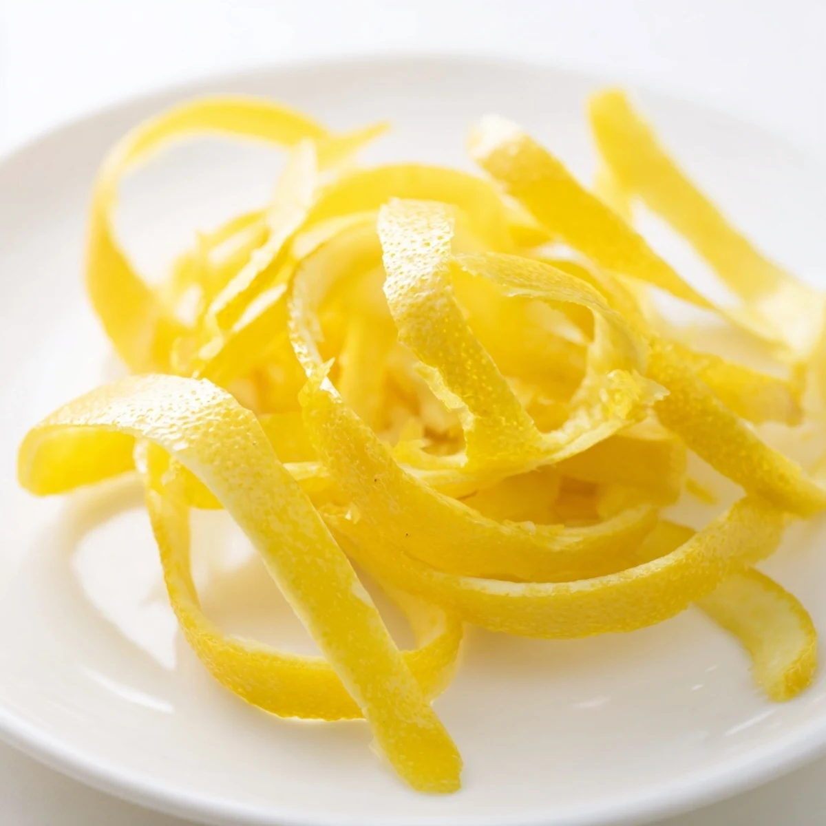 Bright yellow lemon peel being grated on a microplane, ready to infuse vibrant flavor.