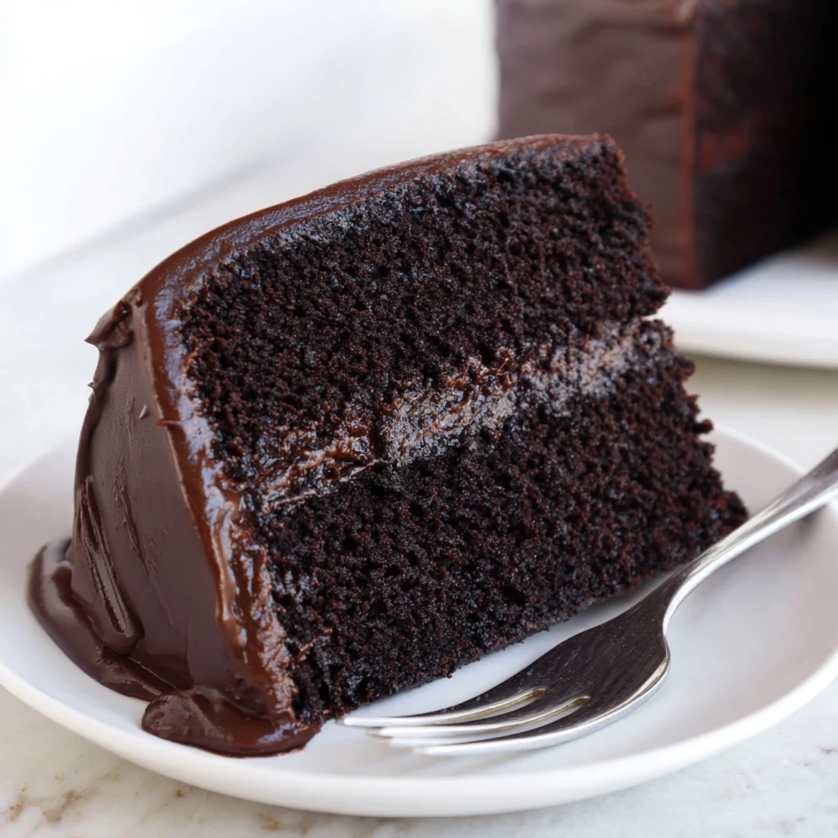 A slice of Rich Chocolate Cake displays a dark, tempting cocoa crumb, perfect for a special treat.