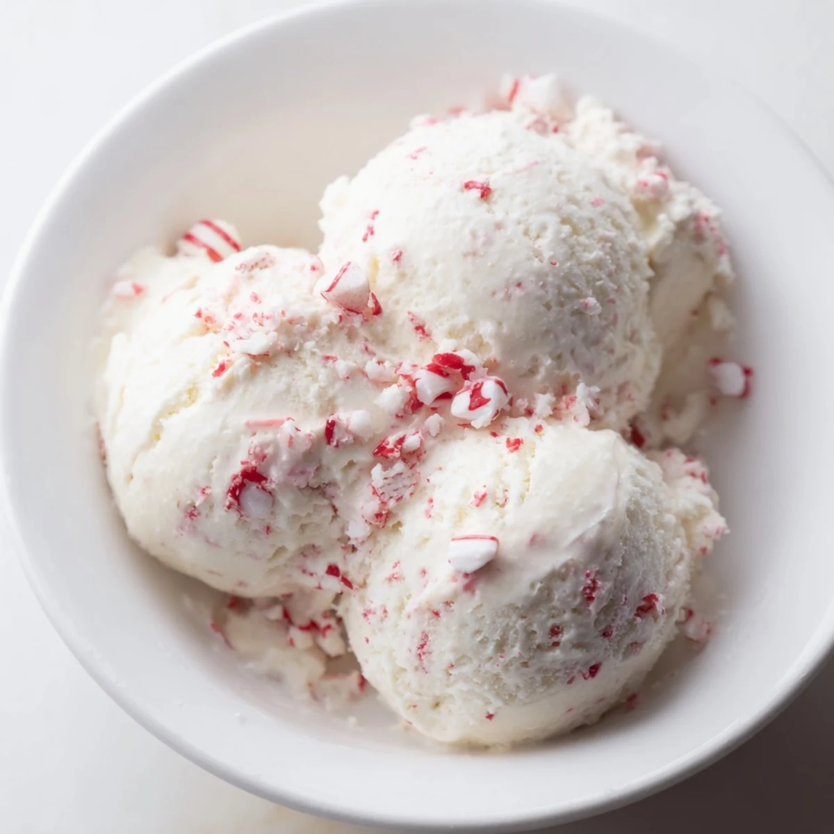 Bright white Peppermint Ice Cream with visible candy bits, perfect for a refreshing holiday treat.