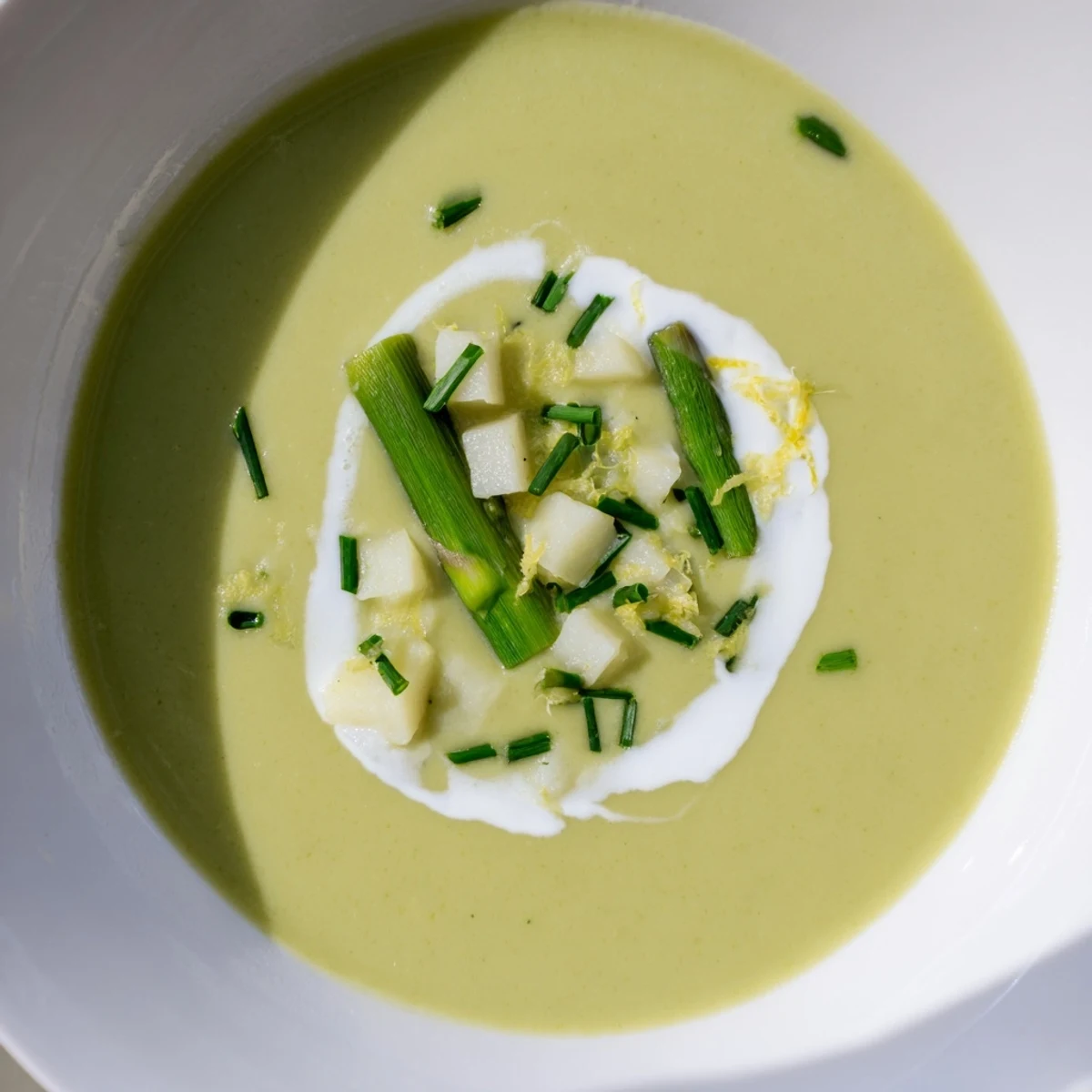 A steaming bowl of creamy asparagus soup, garnished with fresh chives, a flavorful springtime meal.