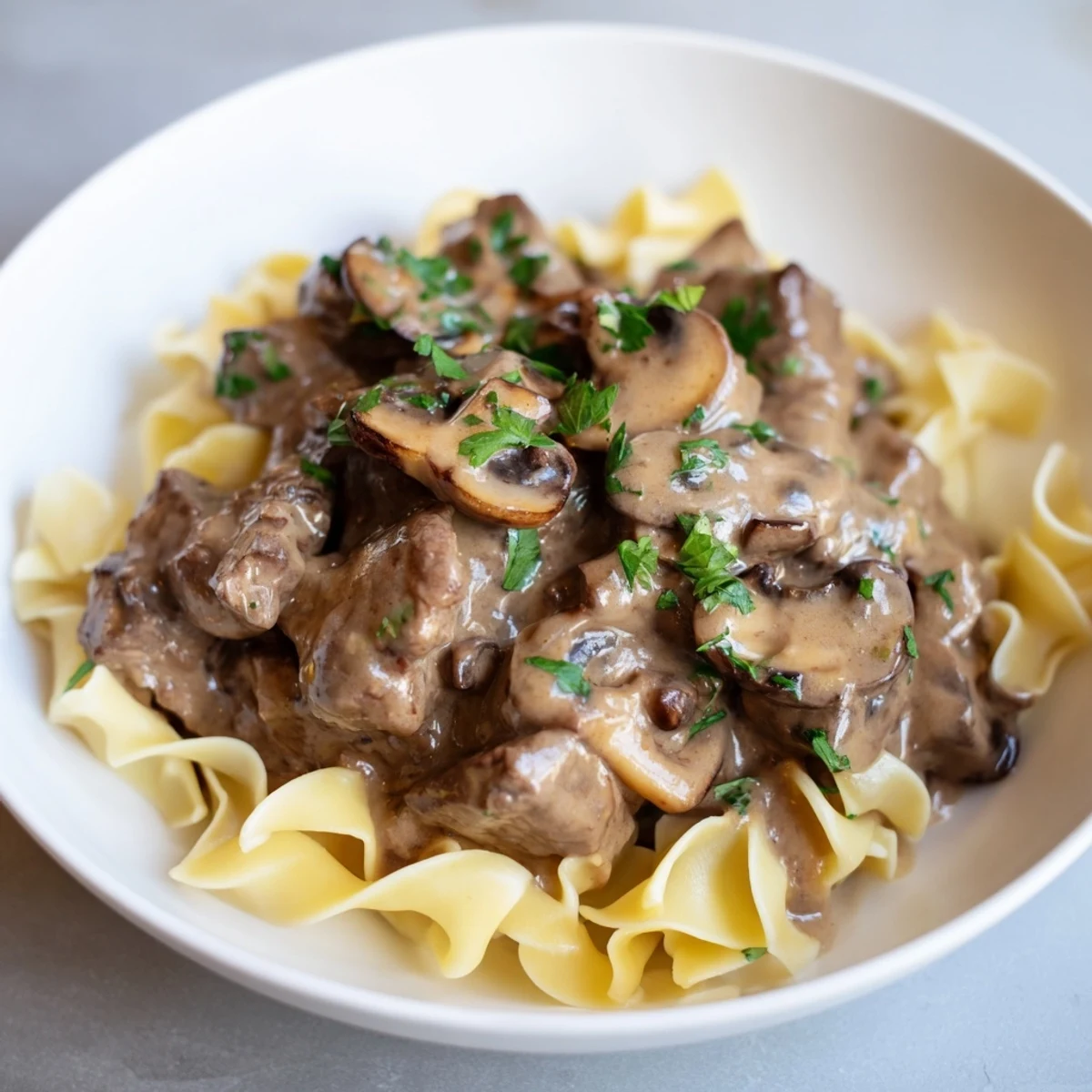 Tender beef stroganoff with rich mushroom gravy, served atop buttery egg noodles, a comforting dinner.