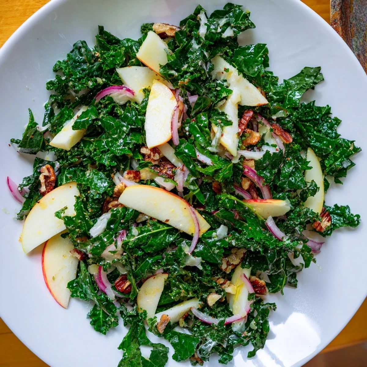 Freshly chopped kale, crisp apple slices, sharp cheddar cubes, and toasted pecans tossed in a vinaigrette in a rustic bowl. Winter Kale Salad with Apple and Sharp Cheddar. 