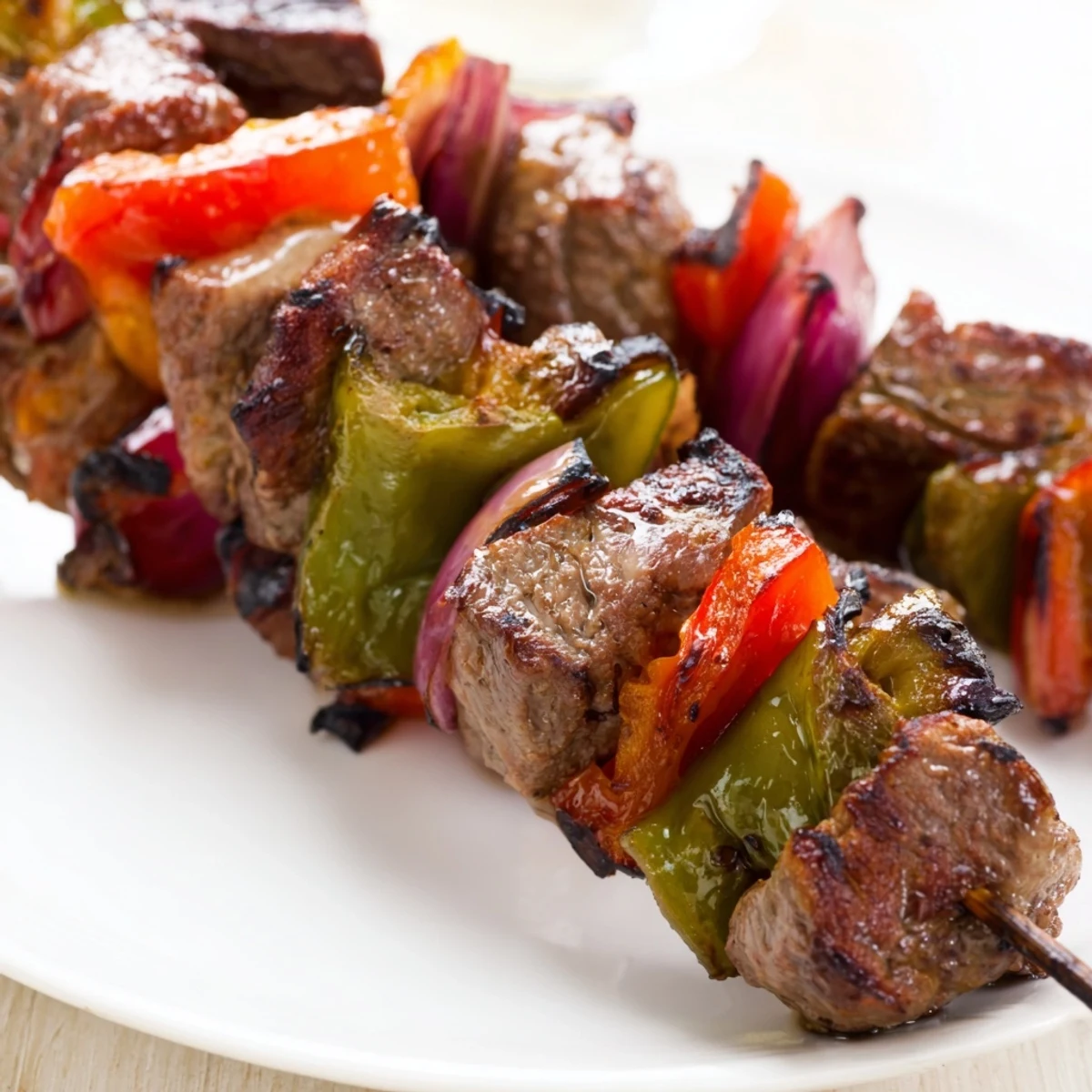 Freshly grilled Beef Kebabs with Bell Peppers and Red Onion rest on a plate, garnished with parsley and ready to be served with rice.