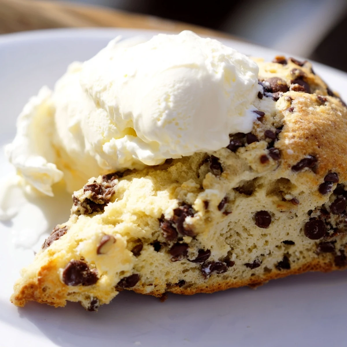 Warm Chocolate Chip Scones with Clotted Cream are topped with a generous dollop of creamy clotted cream.