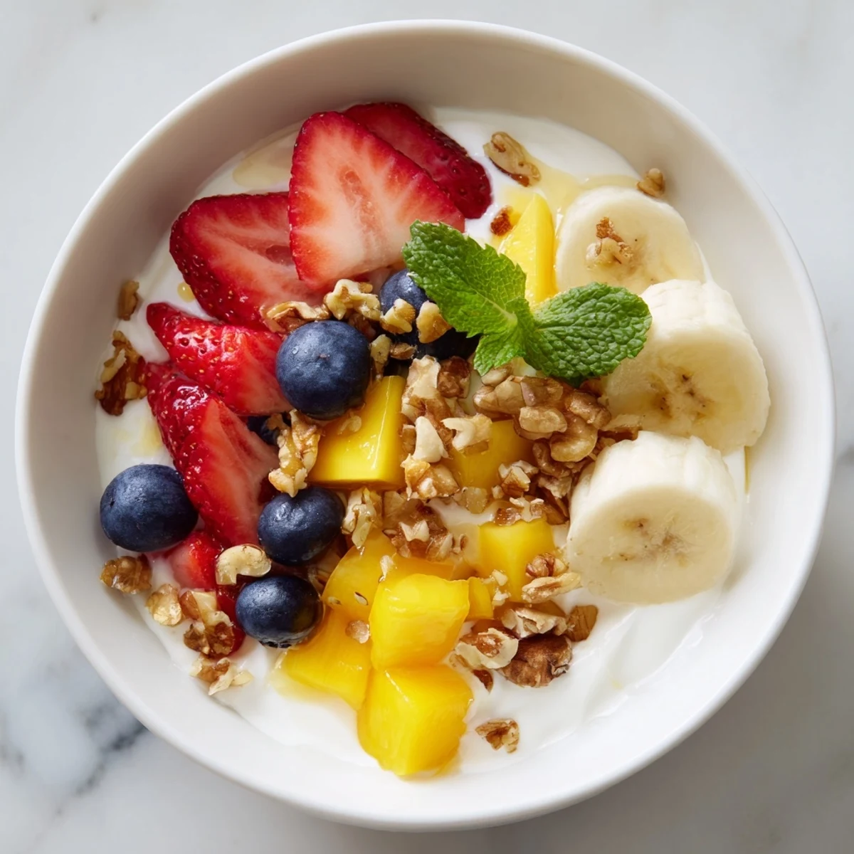 Creamy Yogurt with Fruit parfait in a clear glass, layered with ripe strawberries, blueberries, and diced mango with mint.