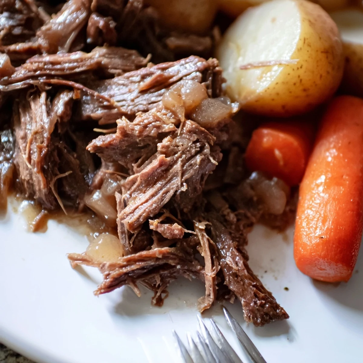 A hearty plate of Slow Cooker Pot Roast with Carrots alongside baby potatoes, onions, and fresh thyme, perfect for a Sunday family dinner.