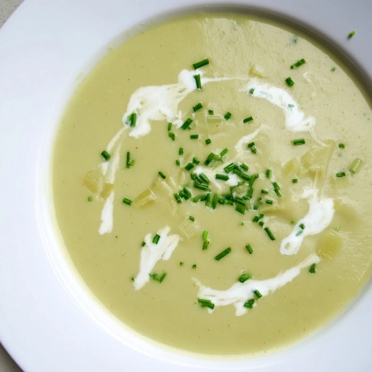 Cozy bowl of leek and potato soup with cream steaming beside crusty bread on a wooden table.  