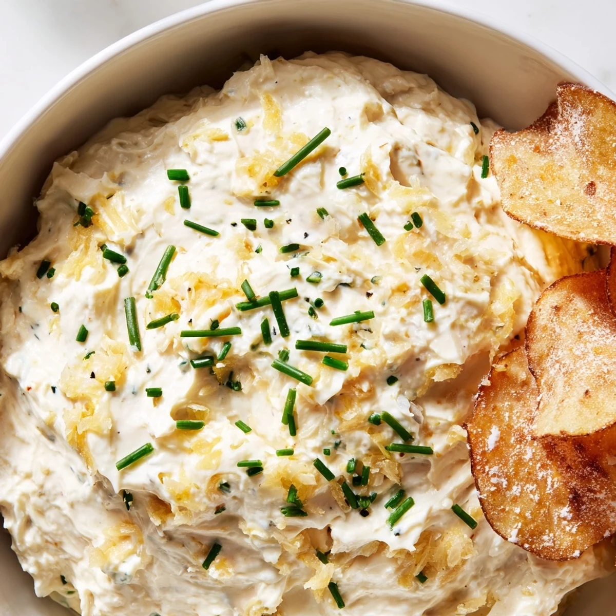 A classic American appetizer of savory onion dip paired with crunchy russet potato chips, ready for game day.