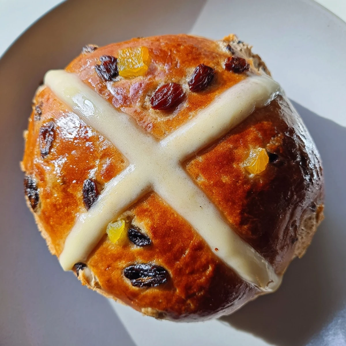 A close-up view of fluffy Easter Hot Cross Buns, studded with vibrant dried fruits and warm spices, arranged in a baking tin.