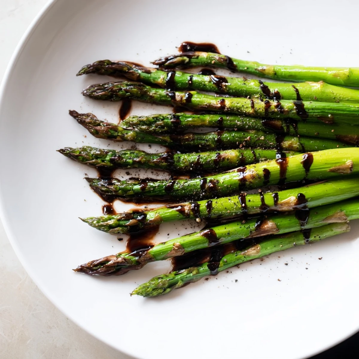 Roasted asparagus with balsamic glaze on a white plate, ready to serve as a simple side dish.  