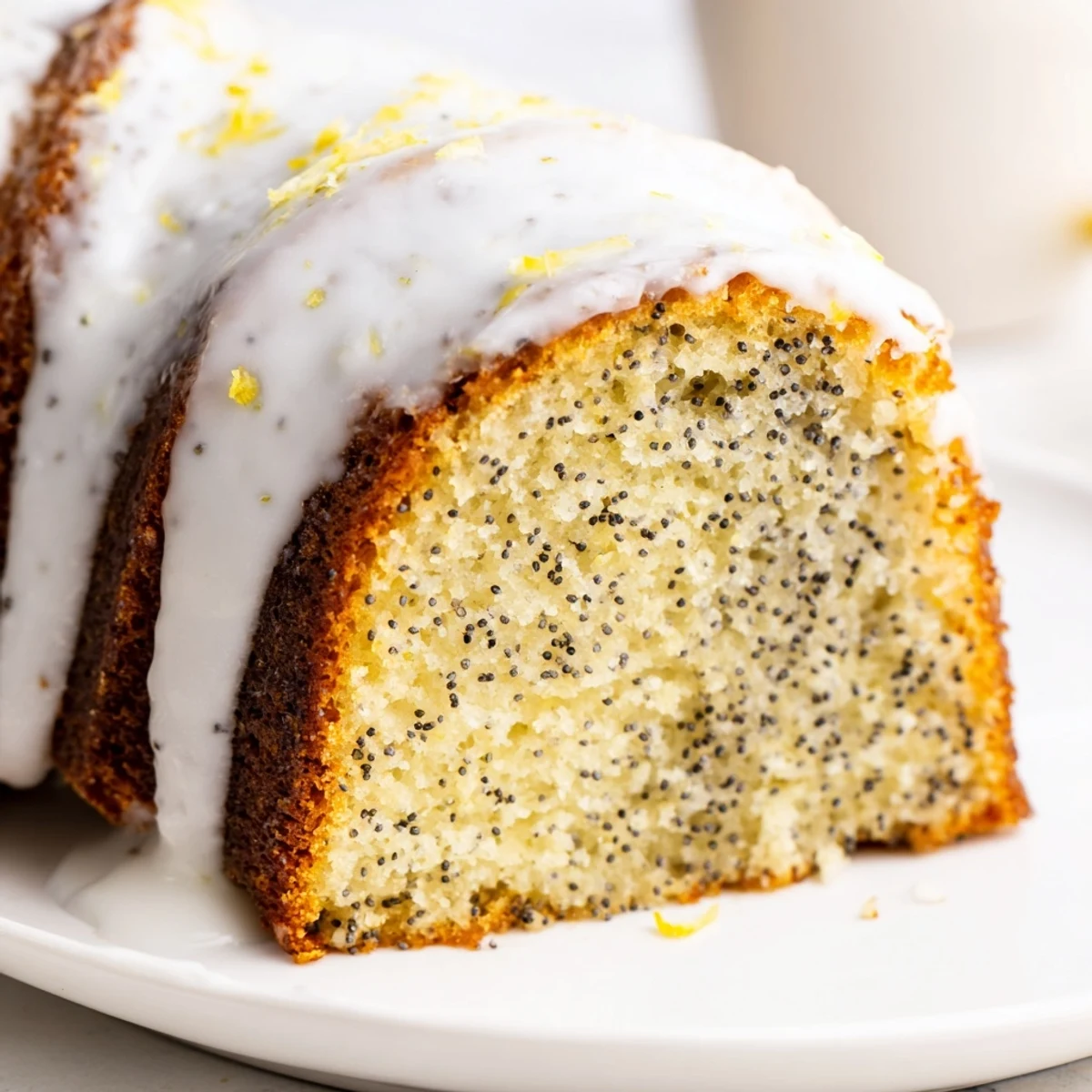 Lemon Poppy Seed Bundt Cake with Icing glistening on a cooling rack, zest and seeds visible in every tender slice.