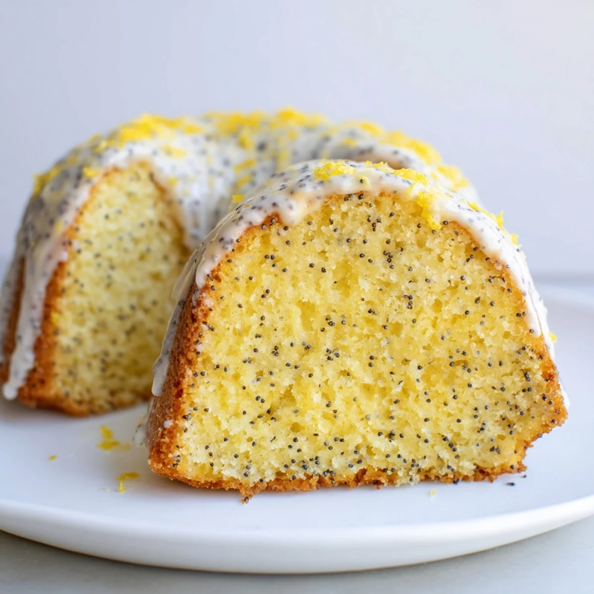 Freshly baked Lemon Poppy Seed Bundt Cake drizzled with tangy lemon icing, served with berries on a white plate.