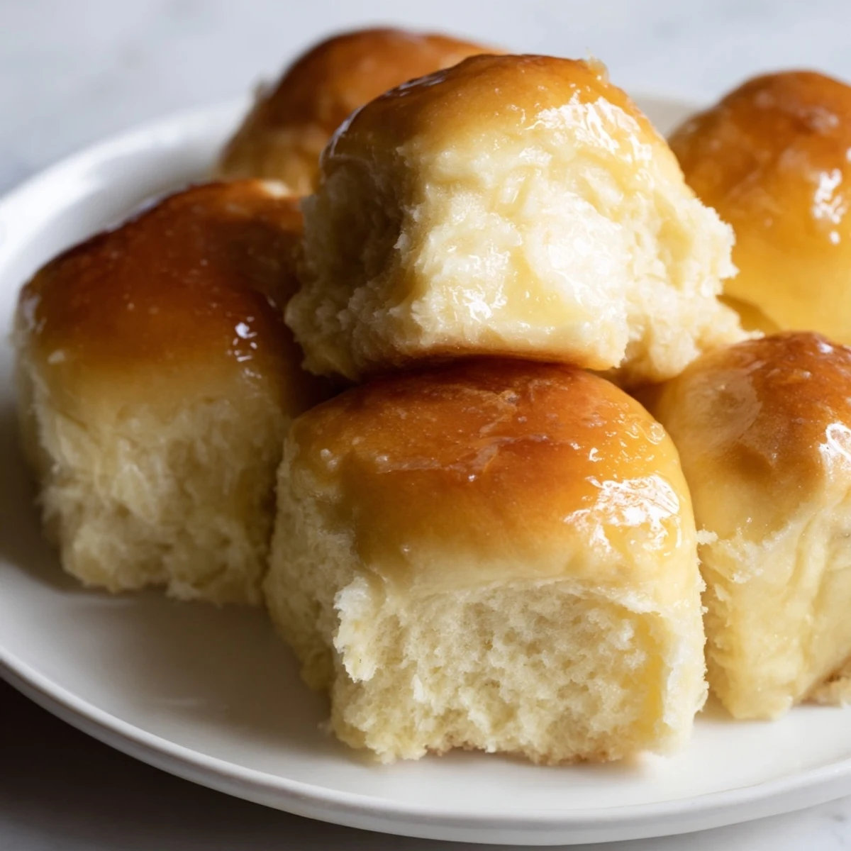 Freshly baked Best Vegan Dinner Rolls with a golden-brown crust and soft, fluffy interior, brushed with melted vegan butter.  