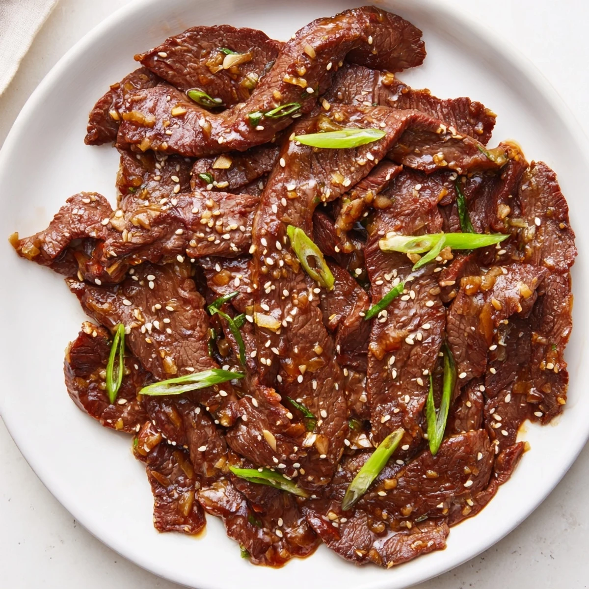 Tender slices of Ultimate Slow Cooker Mongolian Beef glazed in savory-sweet sauce over steamed rice.
