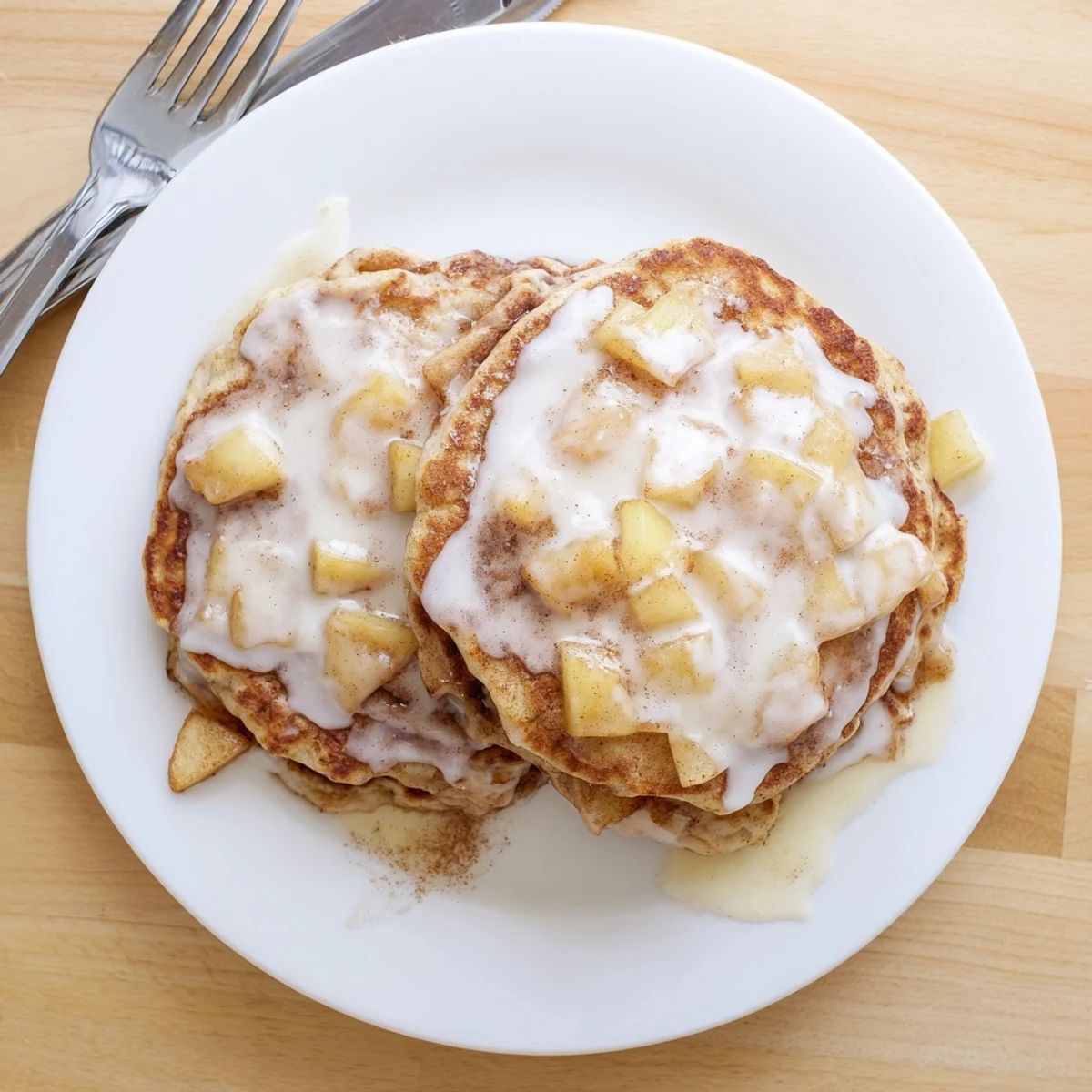 Golden Apple Fritter Pancakes sizzling on a griddle with a sweet vanilla glaze drizzle.