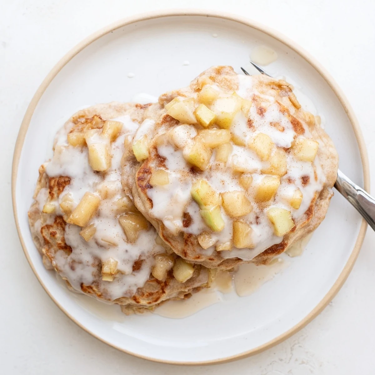 Homemade Apple Fritter Pancakes stacked high with diced apples and a warm cinnamon aroma.
