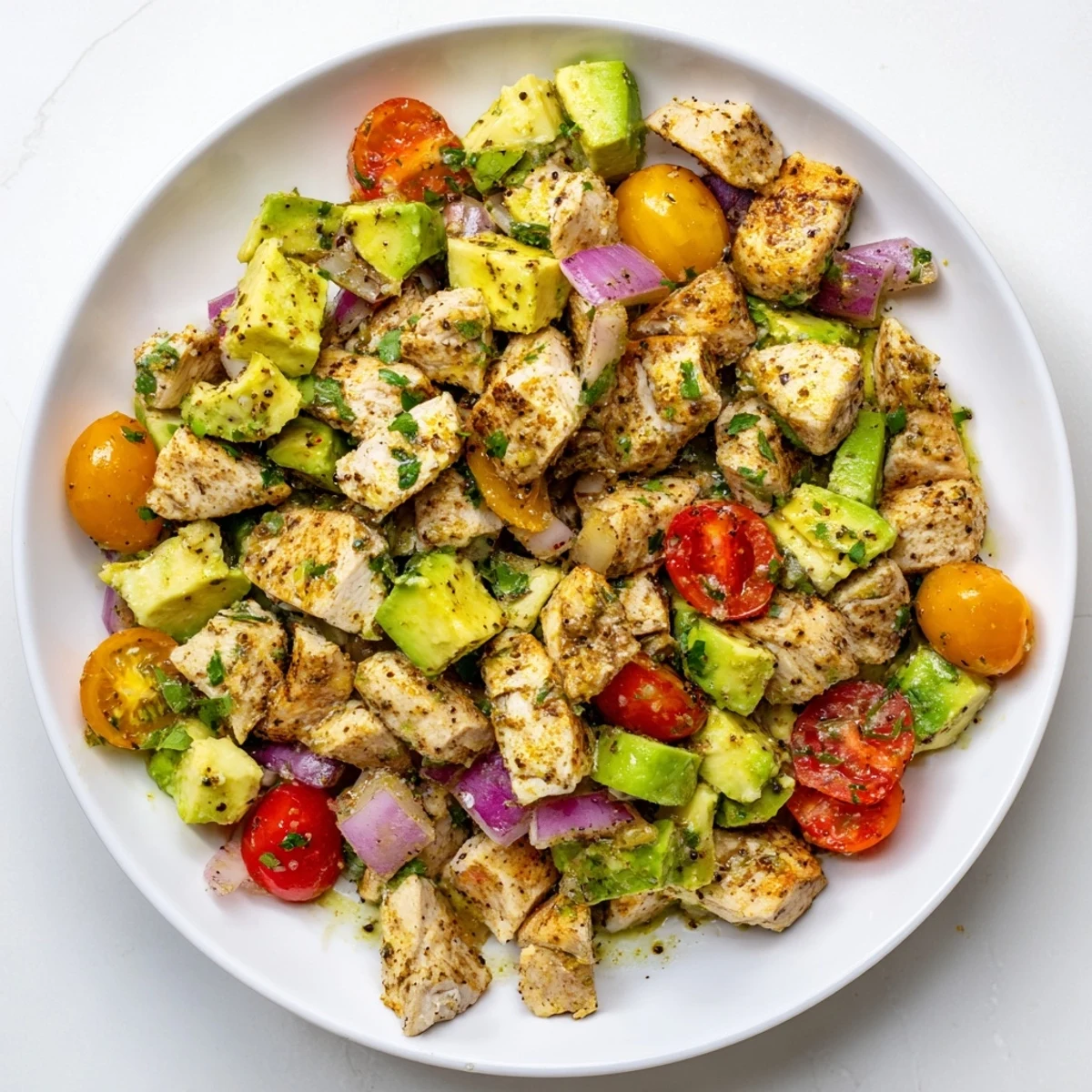 Served over mixed greens, this hearty Avocado Chicken Salad garnished with cilantro is perfect for a light lunch or dinner.