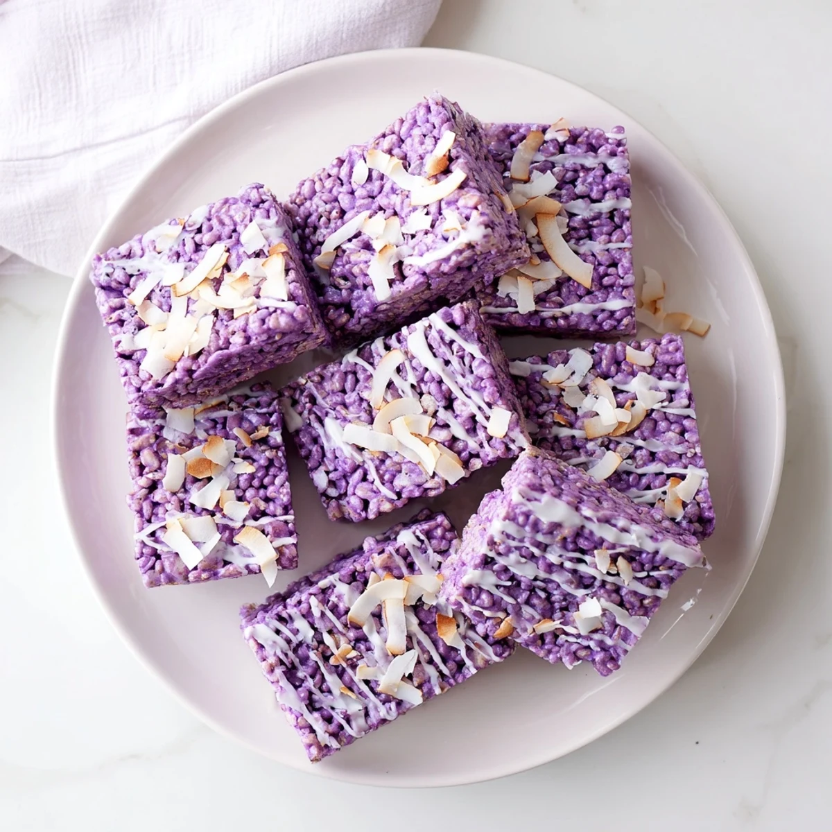 Chewy Filipino-American ube rice krispie treats cut into squares on a white serving plate