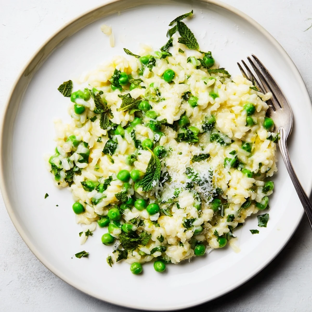 Golden bowl of spring pea risotto garnished with mint and parsley sprigs