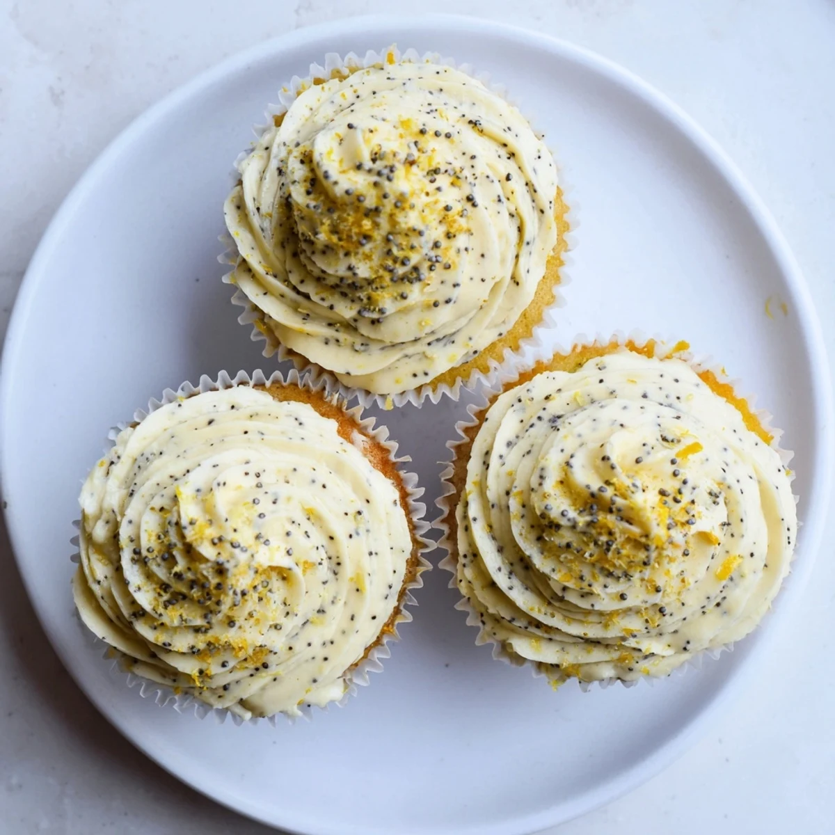 Golden lemon poppy seed cupcakes topped with fluffy cream cheese frosting and zest