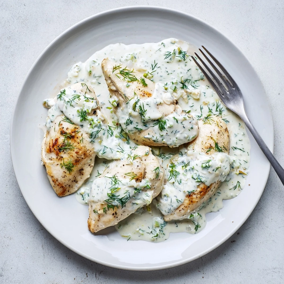 Golden seared chicken breasts resting in a velvety white dill cream sauce