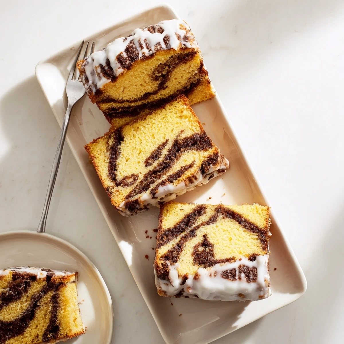Golden cinnamon roll cake with swirling brown sugar ribbons beneath a sweet white glaze