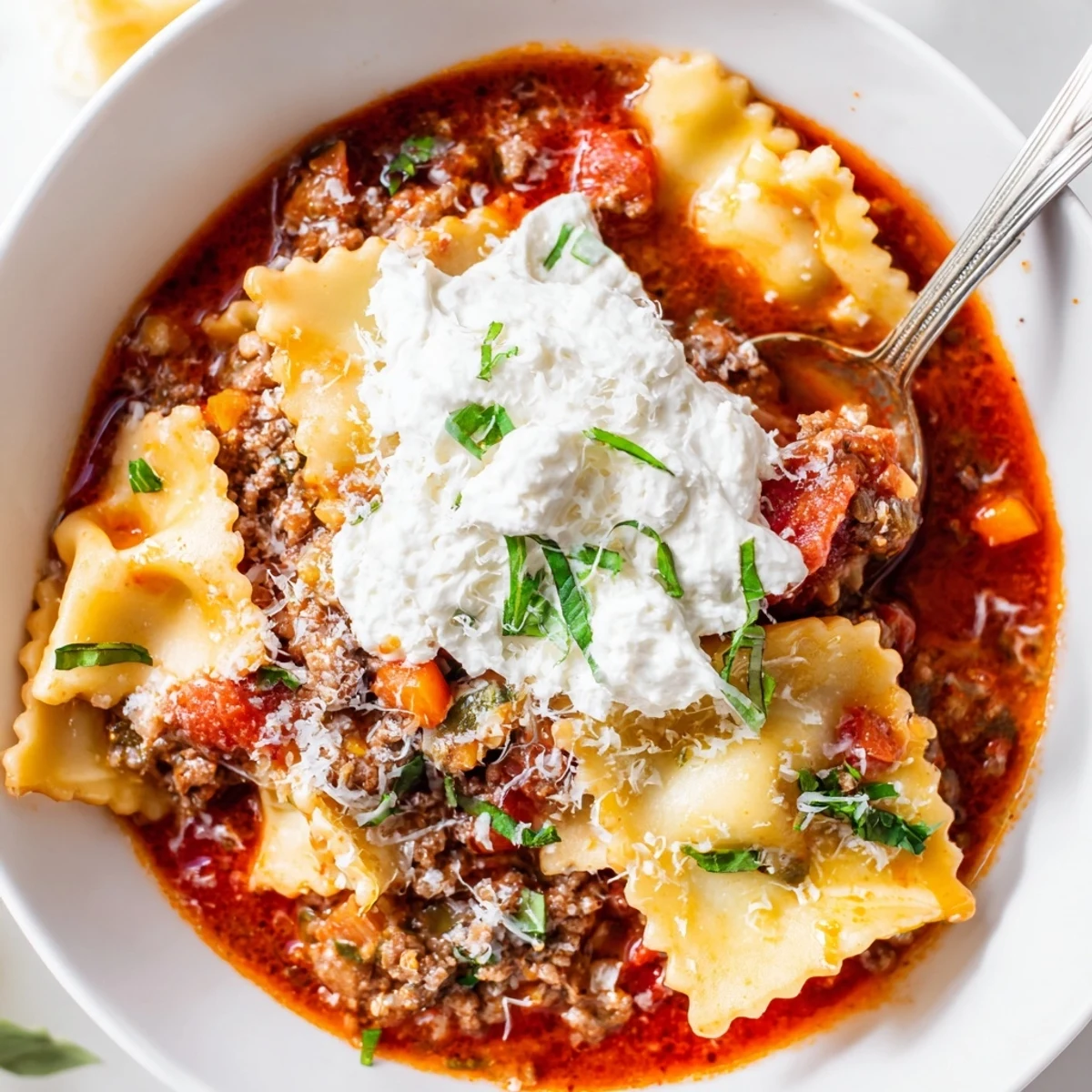 Hearty bowl of Italian lasagna soup topped with creamy ricotta and melted mozzarella cheese