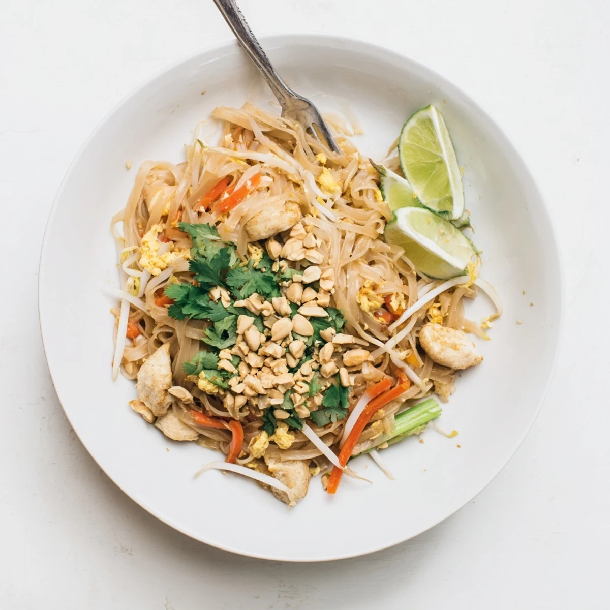 Homemade chicken pad Thai featuring tender chicken strips, colorful vegetables, and roasted peanut garnish