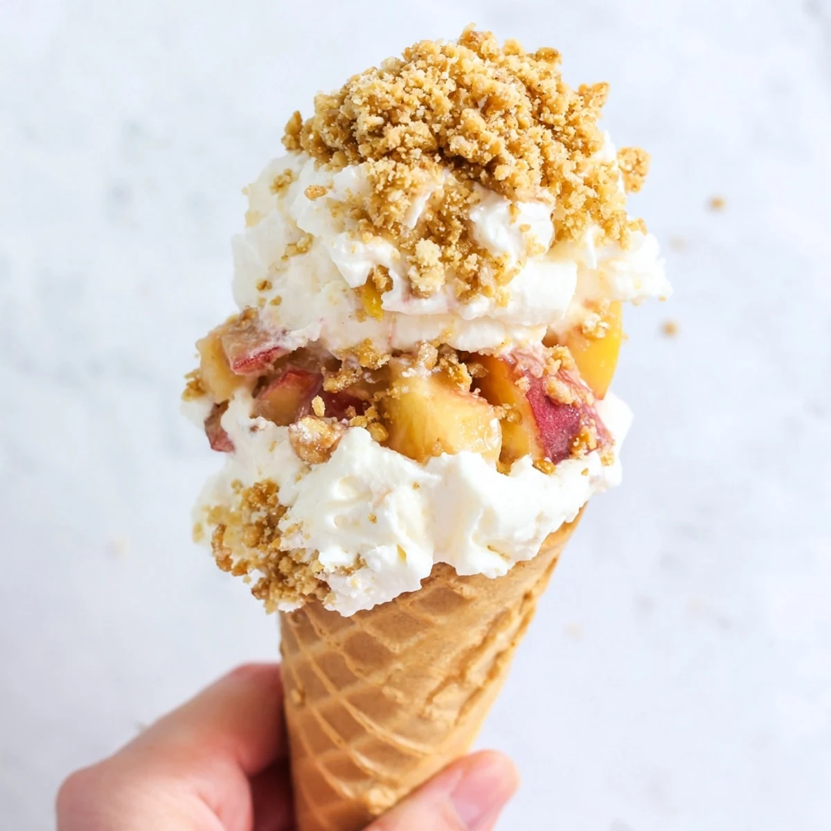 Golden waffle cones overflowing with creamy cheesecake filling and spiced peach cobbler topping