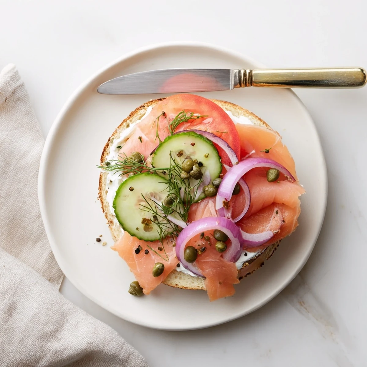 Open-faced smoked salmon bagel sandwich layered with crisp vegetables and fresh dill