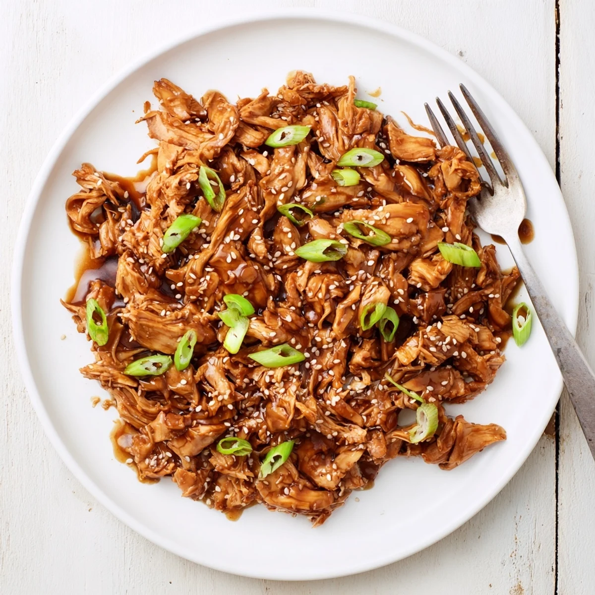 Tender shredded crockpot teriyaki chicken pieces coated in thick sweet savory glaze