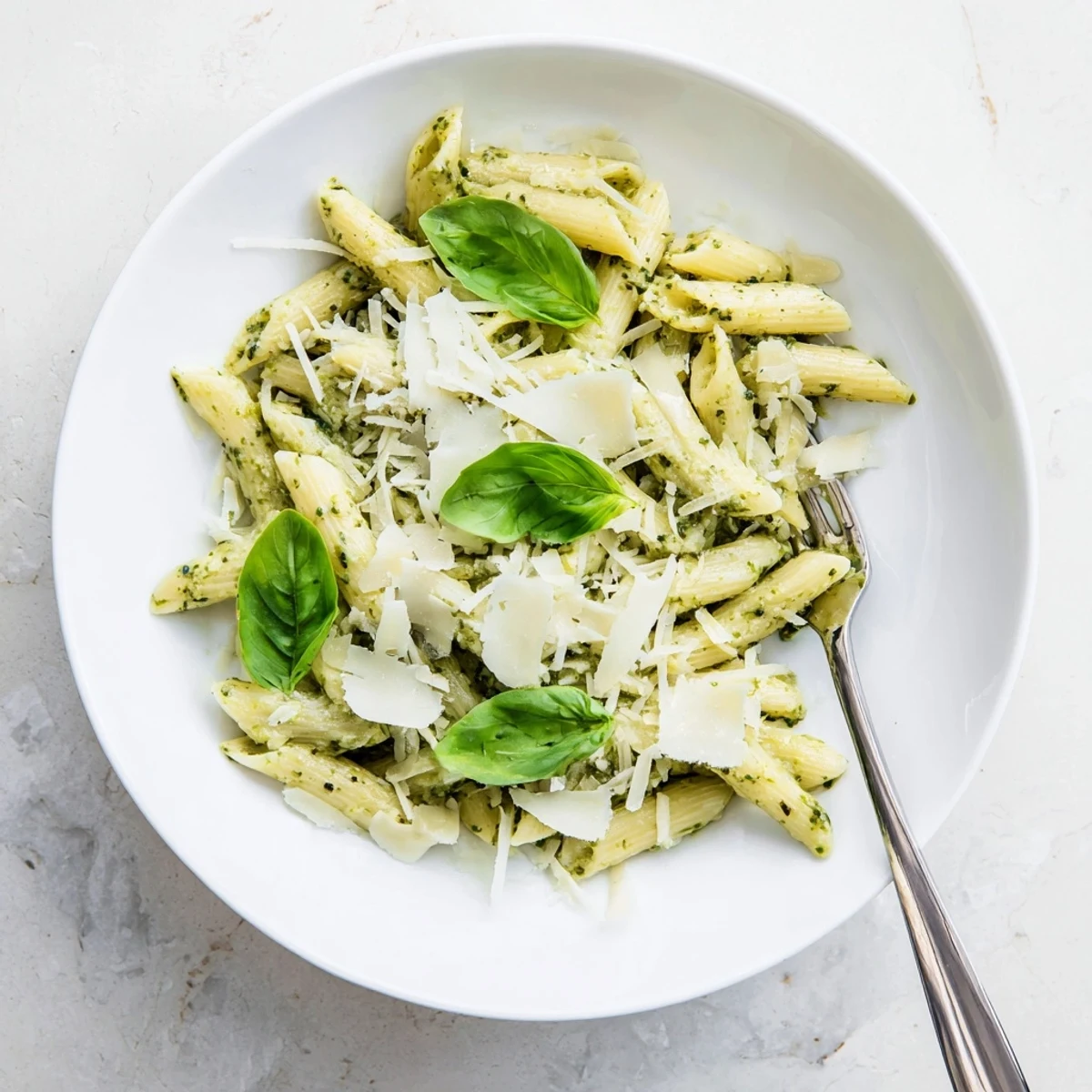 Savory creamy pesto pasta dish featuring silky sauce coating al dente noodles with herb garnish