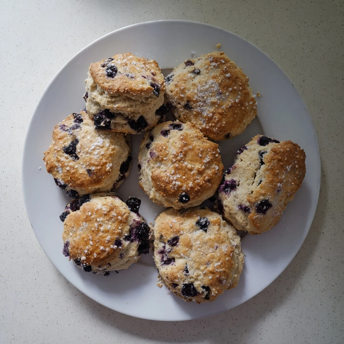 Golden brown blueberry biscuits oozing with purple berries served on wire cooling rack