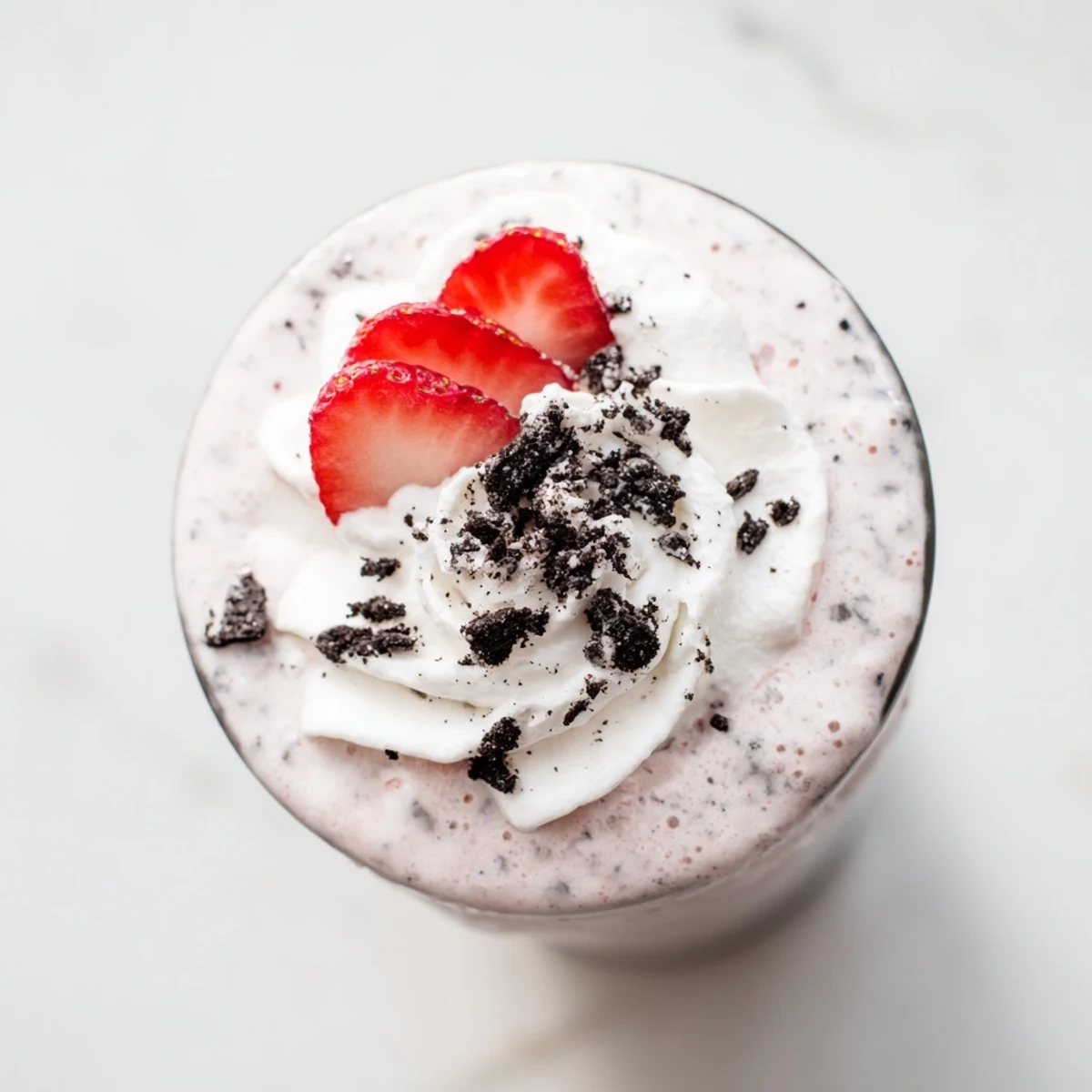 Creamy blended strawberry Oreo milkshake drizzled with chocolatey cookie crumbs and a fresh strawberry garnish