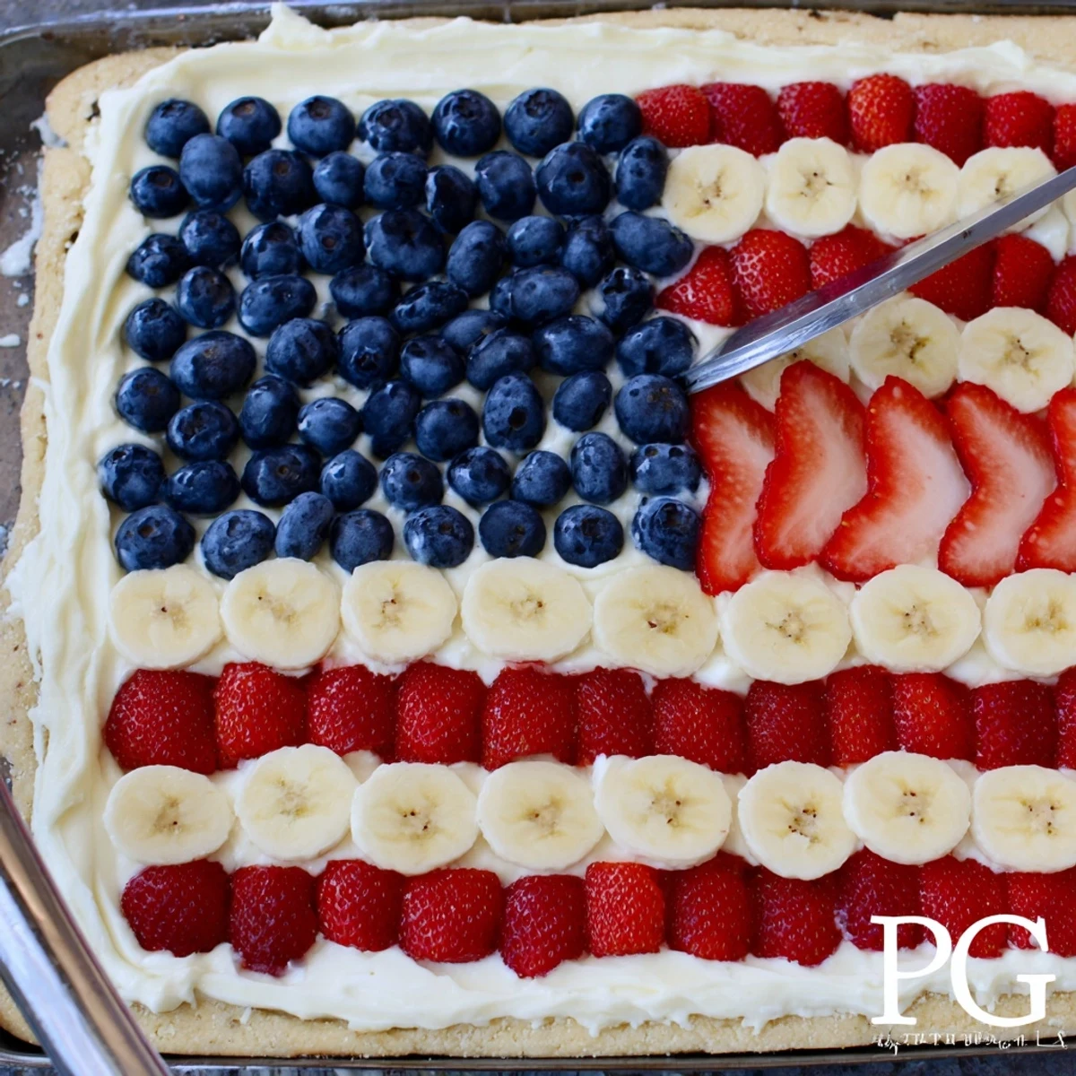 Chilled American Flag Fruit Pizza sliced, bright strawberries and bananas alternating.