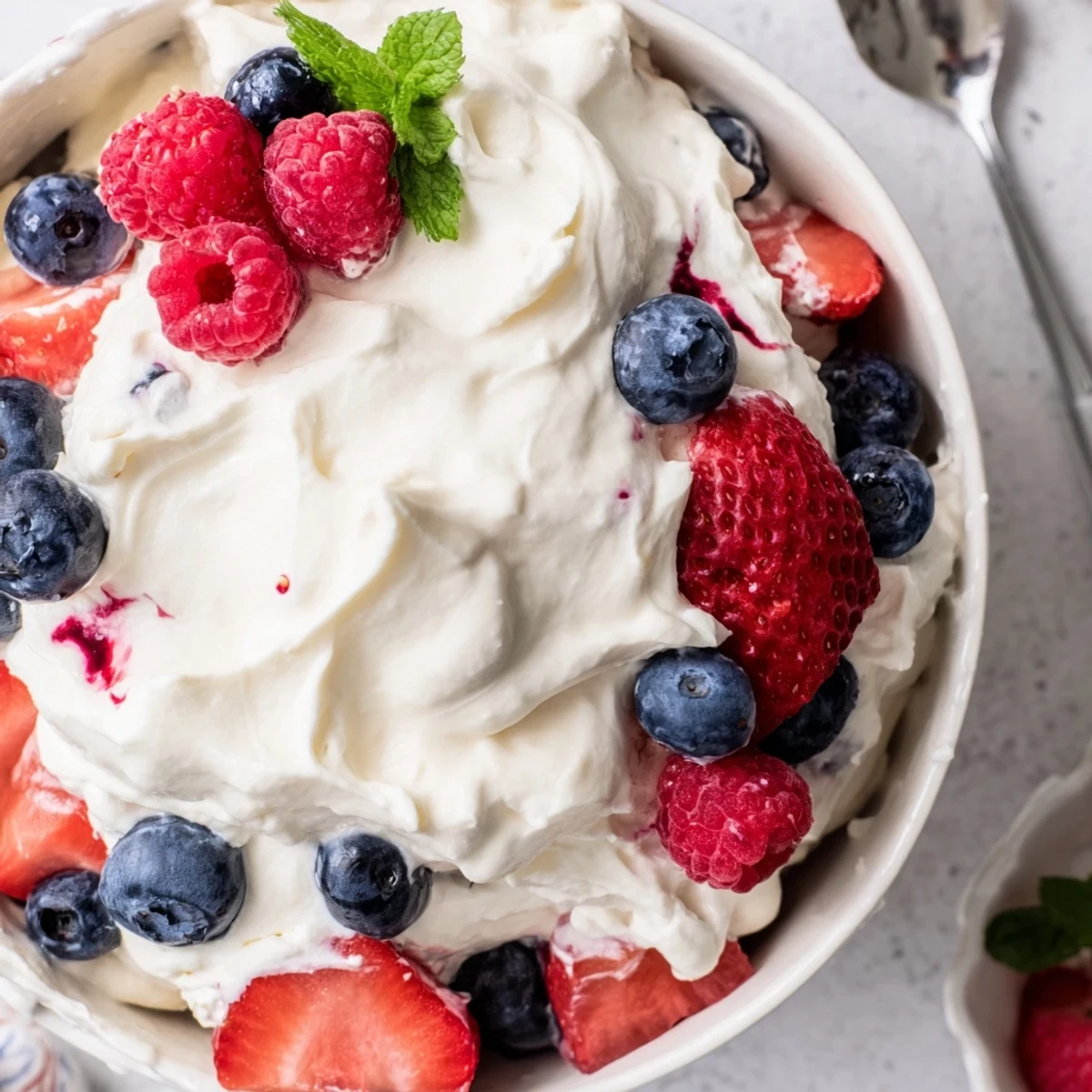 Chilled Red White Blue Cheesecake Salad topped with fresh mint for summer gatherings