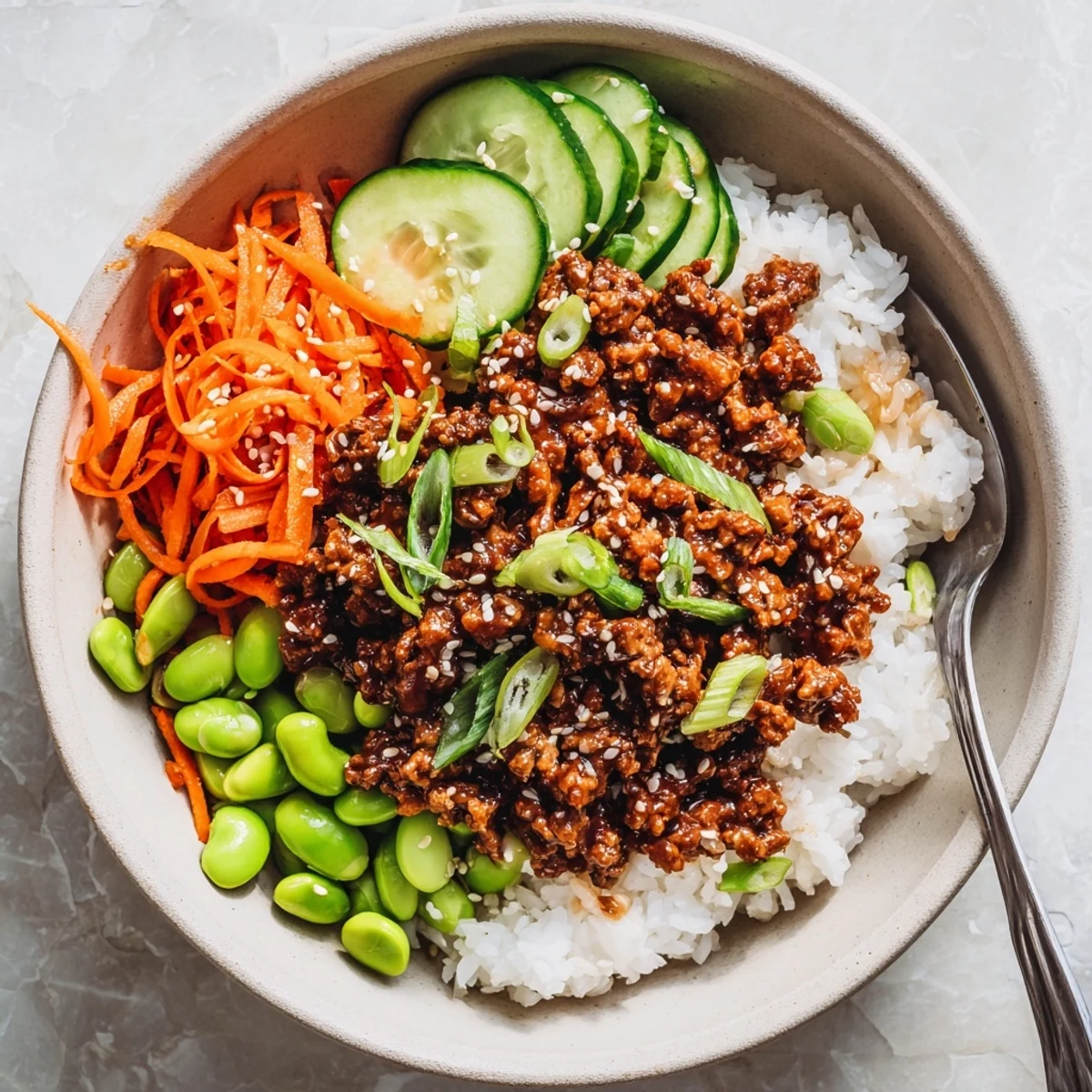 Spicy sweet ground beef hot honey bowl arranged with fresh veggies on a bed of rice