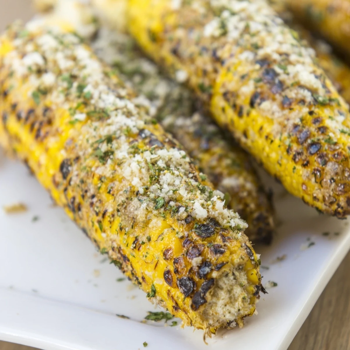 Charred sweet corn ears sprinkled generously with savory ranch parmesan seasoning and fresh green herbs