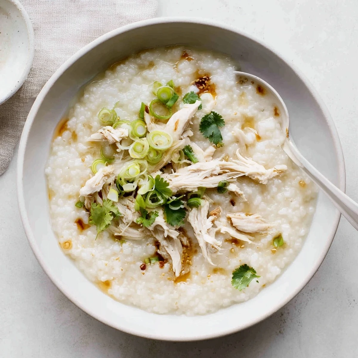 Steamy bowl of chicken congee garnished with fresh cilantro and fried shallots