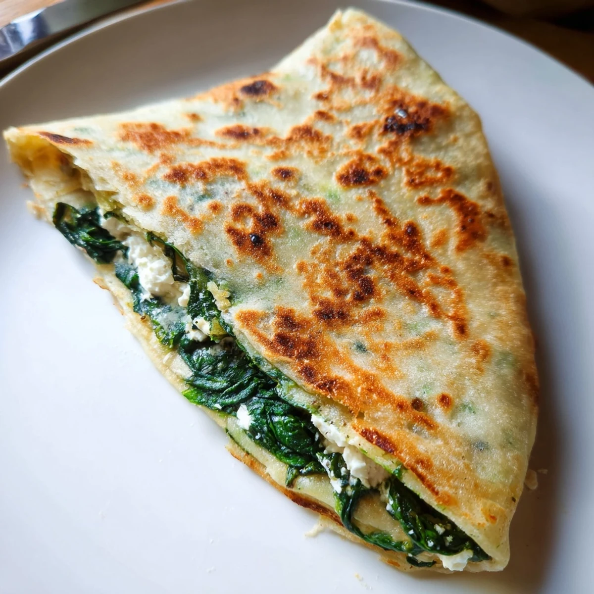 Golden brown Turkish gozleme stuffed with spinach and feta on wooden board