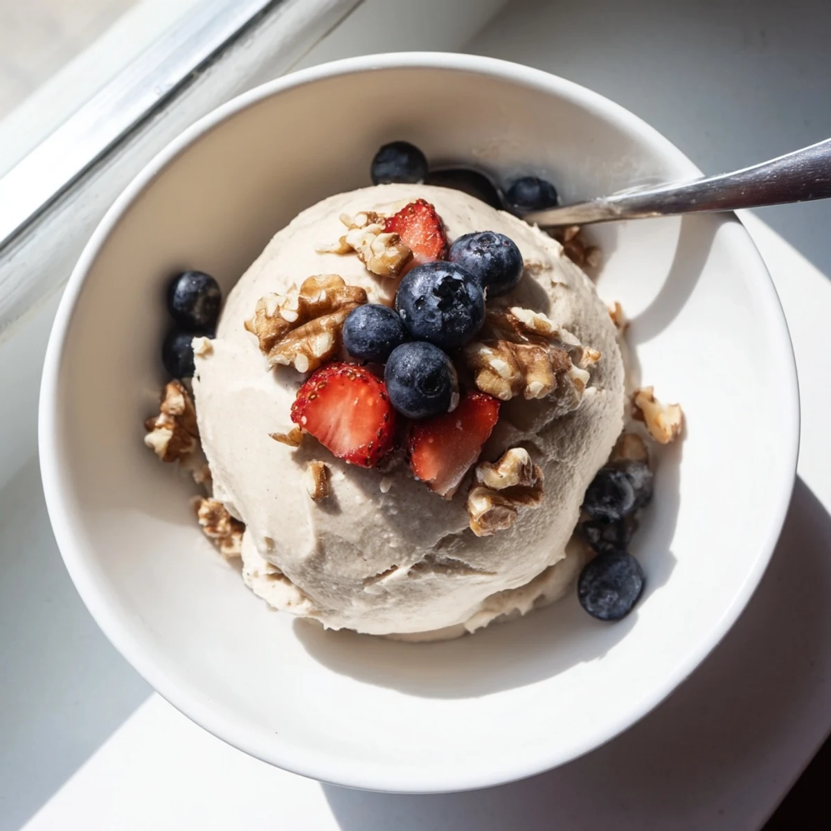 Vegan banana nice cream with smooth soft serve texture swirled in a glass dessert bowl