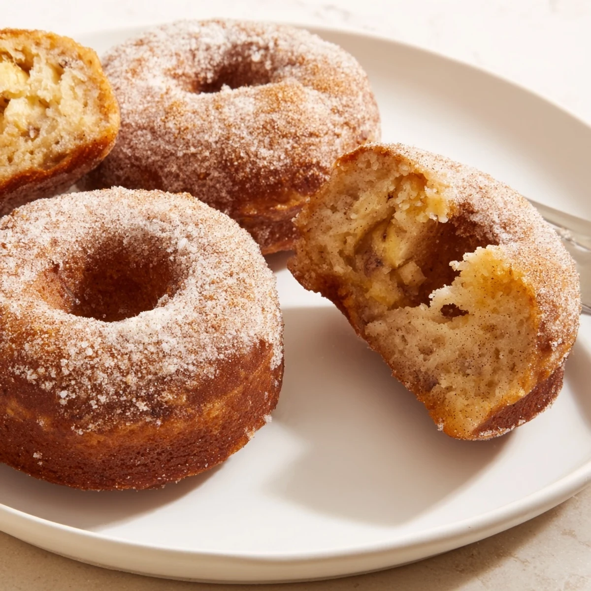 Warm Banana Donuts cooling on a wire rack, golden crumbs and cinnamon.