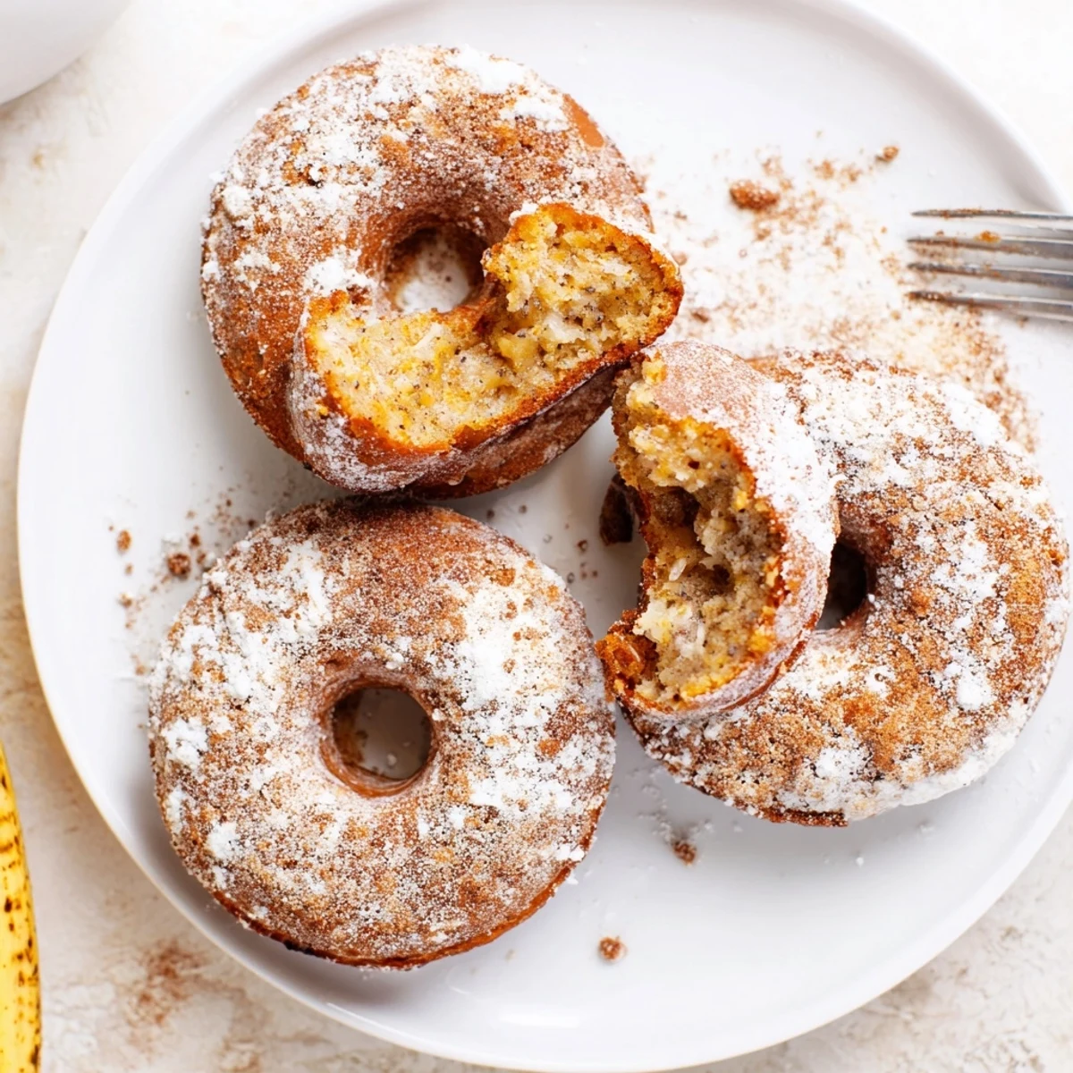 Freshly baked Banana Donuts plated with powdered sugar dusting, ready for breakfast.