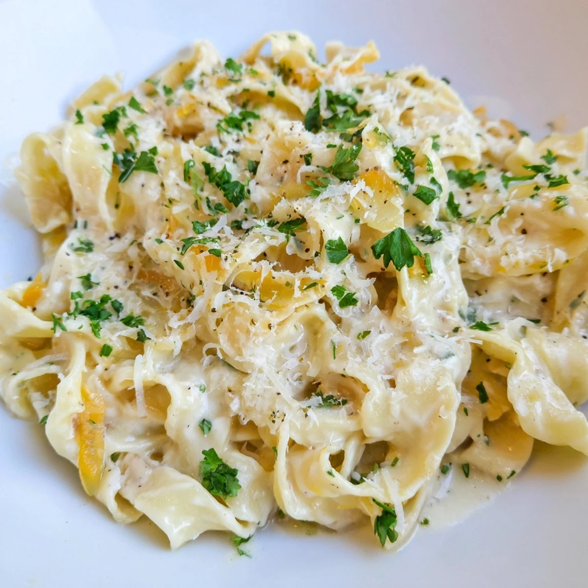 Creamy cafeteria noodles coated in rich Parmesan sauce, garnished with fresh parsley and extra cheese