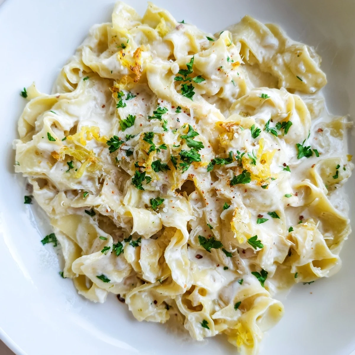 Wide egg noodles swimming in a savory white cream sauce with melted Parmesan and chopped onions