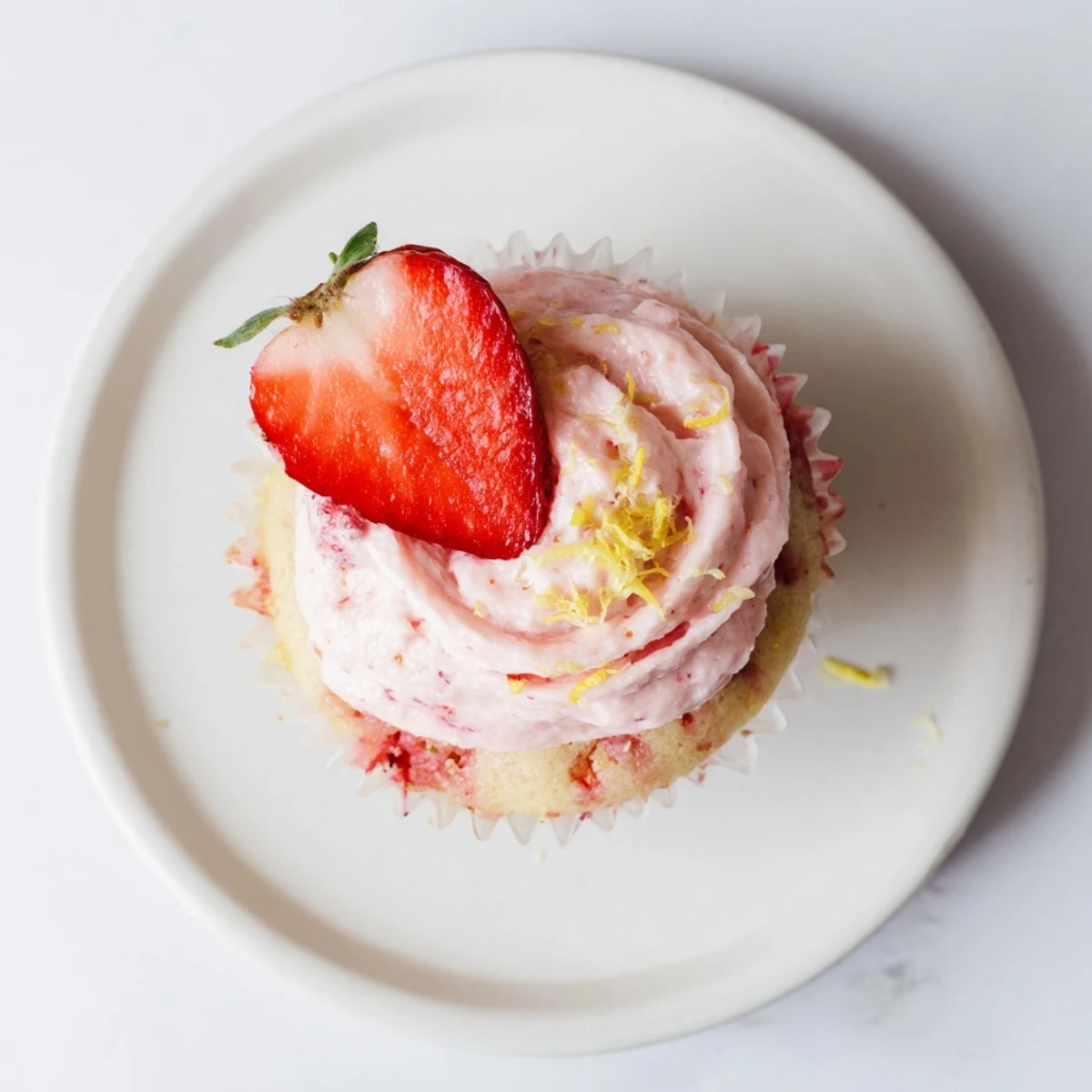 Close-up of Strawberry Lemonade Cupcakes showing pink strawberry buttercream and diced strawberries in the crumb